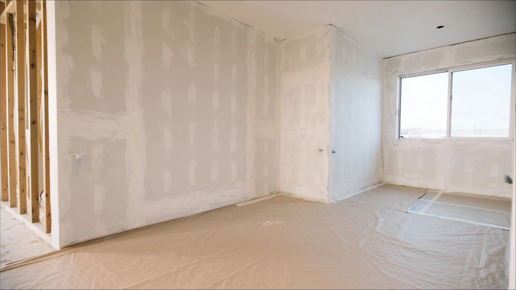 A new-build room with bare, taped drywall before painting